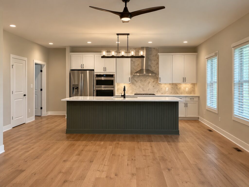 Custom kitchen with white perimeter cabinetry, a dark green island and wood flooring