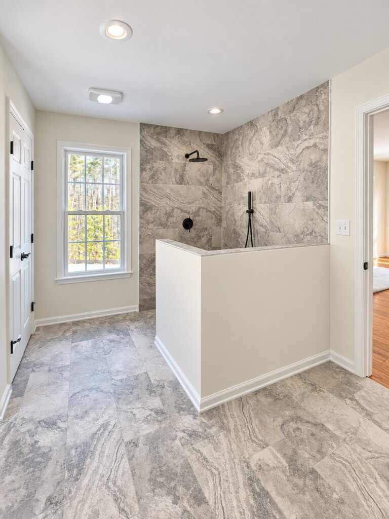 Primary suite bathroom with a marble-tiled walk-in shower and half wall