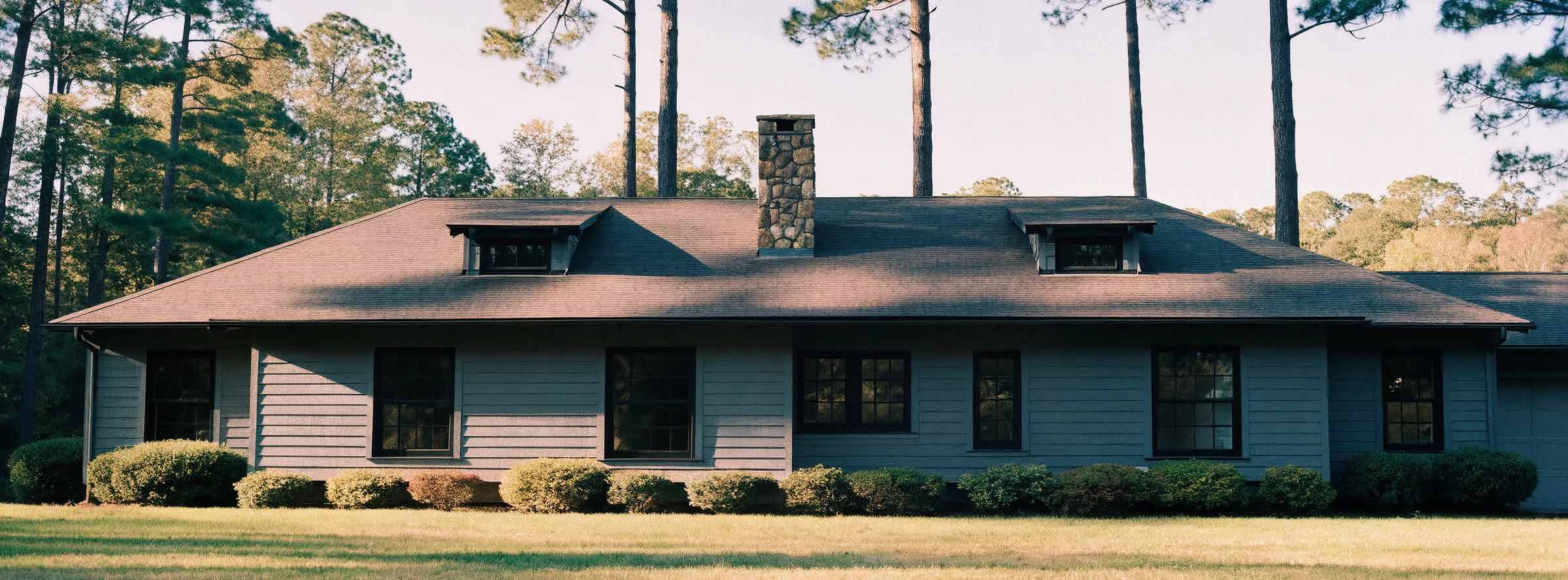 A long low custom home with a fieldstone chimney on a wooded lot at Lake of the Woods, Locust Grove, Virginia